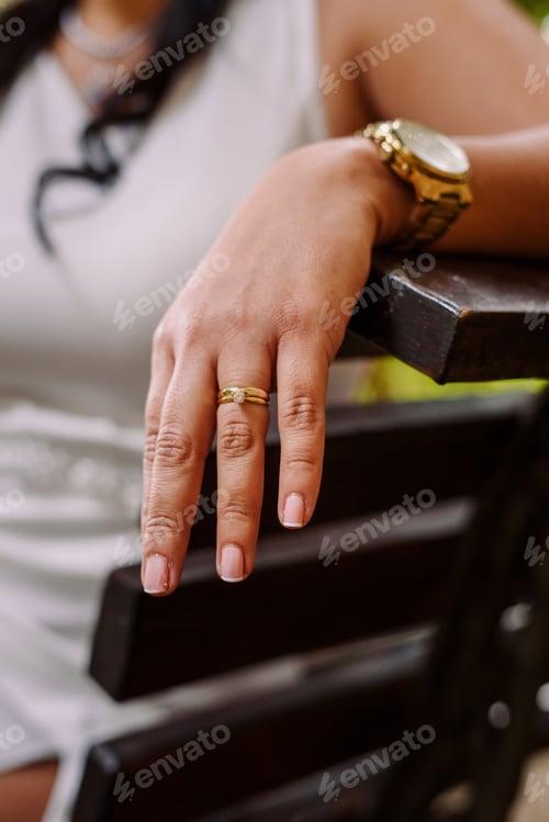 Preview: Wedding ring and gold watch of a bride resting on a chair during her wedding day