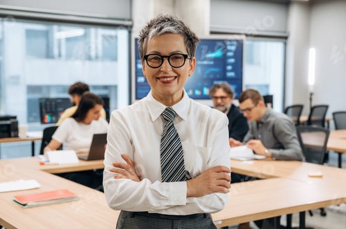 Preview: Confident businesswoman in a modern office setting, smiling with arms crossed, surrounded by colleag
