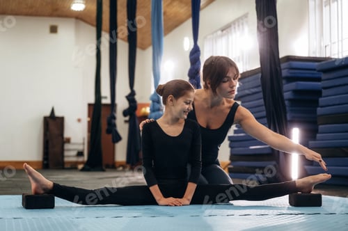 Preview: Professional help, learning. Female instructor helping a child practice yoga in a fitness studio