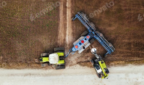 Preview: Aerial view of two agricultural tractors working together on a field, one pulling a blue plow while