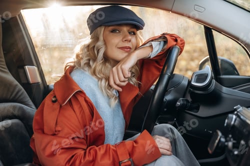 Preview: Sitting and looking at the camera, resting. Happy blonde woman is in her electric car