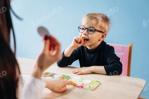 Preview: Preschool child with glasses engaged in learning activity with teacher, colorful educational cards d