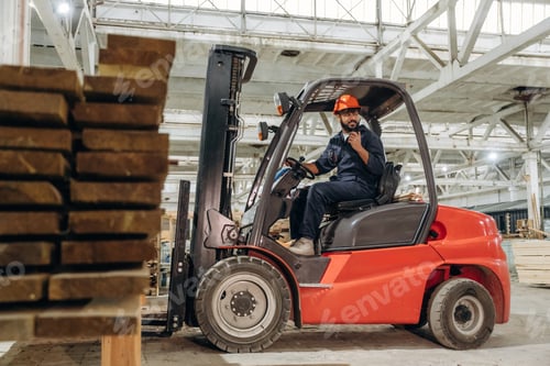 Preview: Heavy material, lifting the planks. Warehouse worker operating a forklift while handling wooden mate