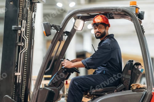 Preview: Warehouse worker operating a forklift while handling wooden materials