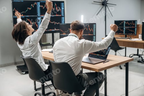 Preview: Hands are up, celebrating success. Two male exchange workers are in the office together