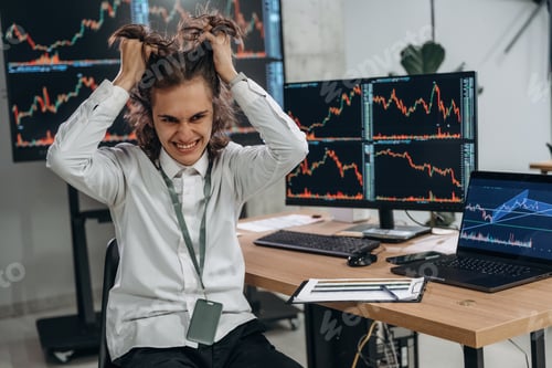Preview: Young man is sitting in the office with multiple displays of stock market data