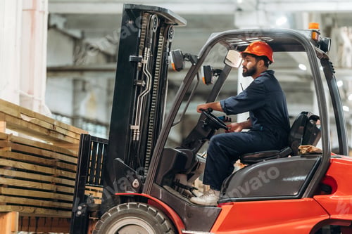 Preview: Lifting bunch of planks. Warehouse worker operating a forklift while handling wooden materials