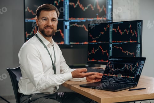 Preview: Bunch of screens with data. Handsome businessman is in the office with stock exchange market informa
