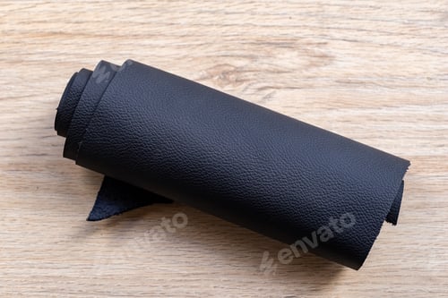 Preview: Black leather roller, on a wooden surface