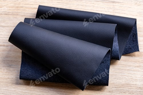 Preview: Black leather roller, on a wooden surface
