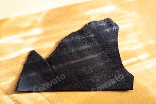 Preview: Black Leather Offcut on Textured Surface – Natural Material Scrap Close-Up
