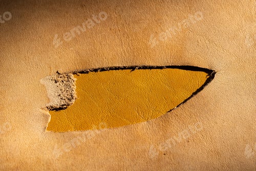 Preview: Torn Beige Leather Surface Revealing Yellow Layer Underneath, Damaged Leather Material Close-Up