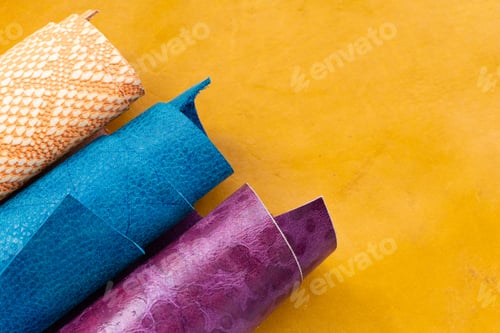 Preview: Colorful Rolled Leather Hides in Orange Blue and Purple Tones on Yellow Background