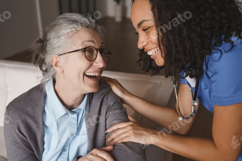 Preview: Senior woman and nurse laughing together at home, healthcare support, joyful communication