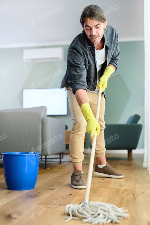 Preview: Cleaning, home and man with mop for floor maintenance, hygiene and chore routine in living room