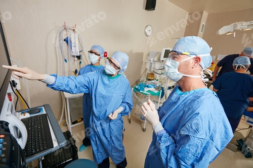 Preview: Surgeon, team and point at monitor with meeting, talk and emergency room with insight at hospital