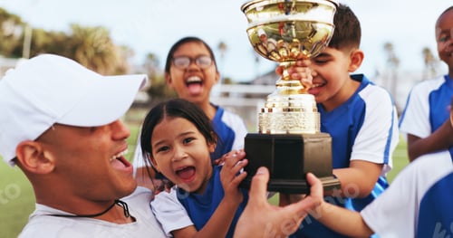Preview: Excited, coach and kids with trophy on field, soccer tournament success and celebration victory