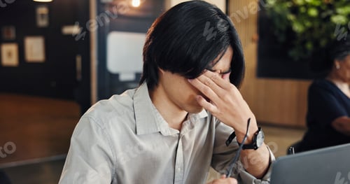 Preview: Man, laptop and glasses with headache at office, stress or eye strain with tired at media company