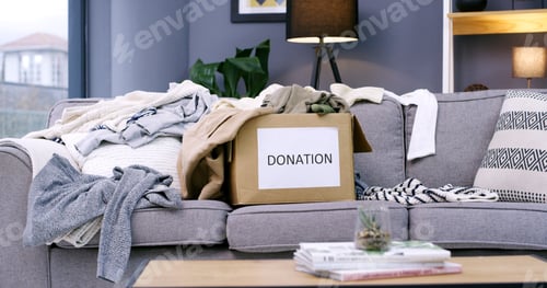 Preview: Donation, empty and box with clothes on sofa in home for for charity, giveaway and welfare