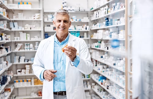 Preview: Mature, happy man or portrait of doctor with pills in dispensary for medical antibiotics or cure