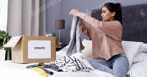 Preview: Woman, folding clothes and donation box in home for charity initiative, nonprofit
