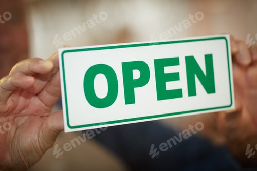 Preview: Hands, open sign and window of coffee shop with person hanging notice at door or entrance