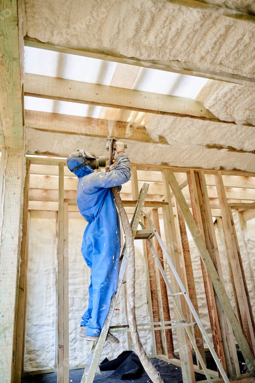 Preview: Insulation worker spraying polyurethane foam onto ceiling beams inside timber frame house
