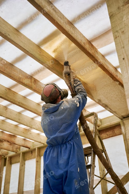 Preview: Worker spraying polyurethane foam insulation under roof in timber frame house