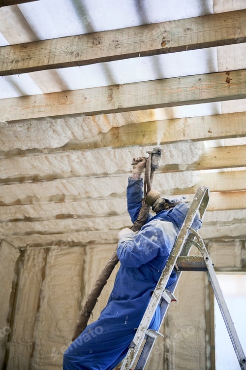Preview: Worker spraying polyurethane foam insulation under roof beams inside timber frame house