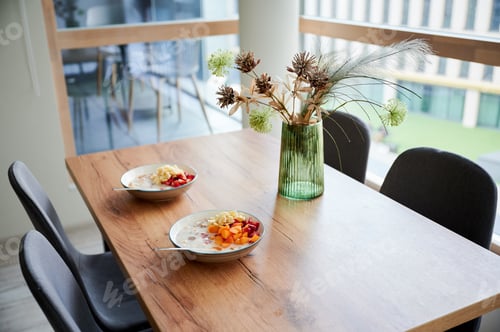 Preview: Two bowls of cereal with milk and fresh fruit on dining table, breakfast served in modern home