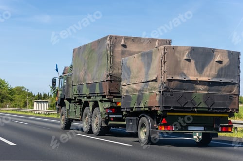 Preview: Europe military truck camouflage drives along autobahn green forest landscape during summer daylight