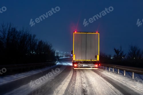 Preview: Night winter highway scene freight truck driving icy snow covered road red taillight darkness harsh