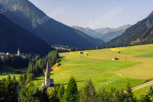 Preview: Scenic alpine chapel with tall spire stands green hillside surrounded forest rural landscape. Peacef
