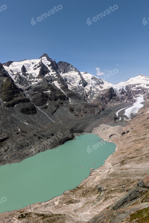 Preview: Alpine mountain range massive Grossglockner glacier descending rocky valley turquoise lake clear blu