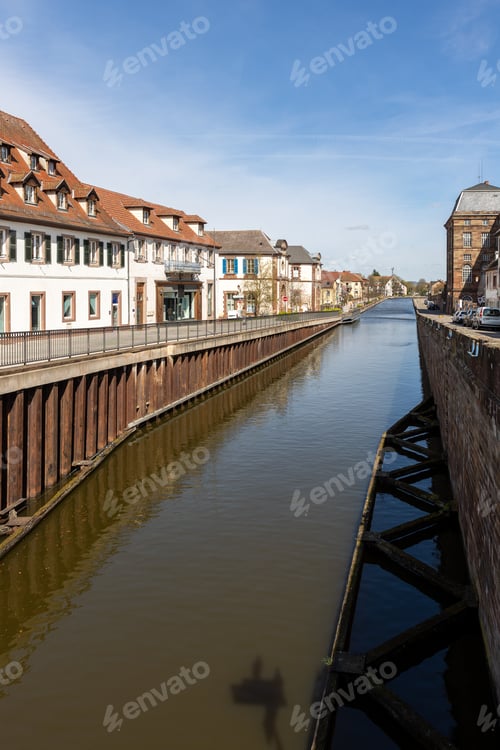 Preview: Saverne canal Alsace historic architecture dormer roofs stone embankment calm waterway under blue sk
