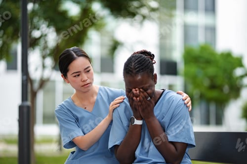 Preview: Nurse comforting a crying colleague experiencing burnout outdoors