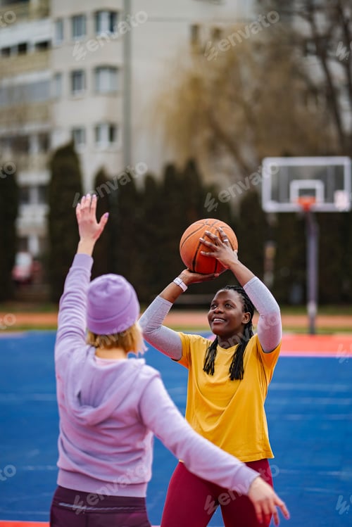 Preview: Diverse women playing basketball on urban outdoor court