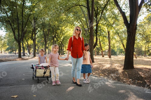 Preview: Mother and daughters walking in the park, pulling a wagon