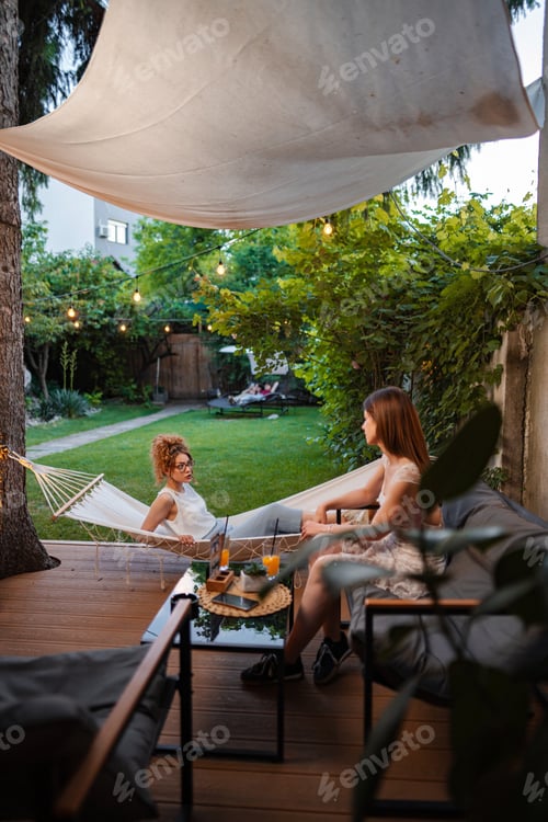 Preview: Friends relaxing in hammock on summer patio
