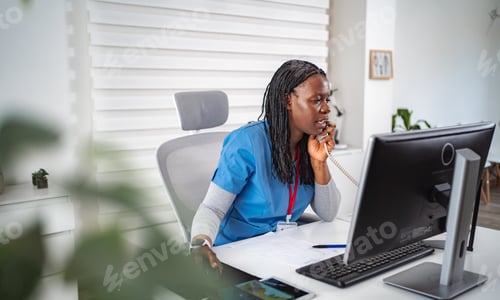 Preview: Medical professional talking on phone while working at desk
