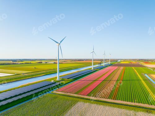 Preview: Aerial view of Dutch countryside with wind turbines and solar panels among green fields.