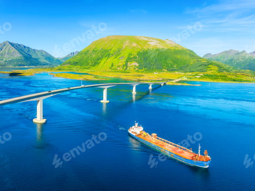 Preview: Aerial view of a cargo ship passing under a bridge with car traffic.