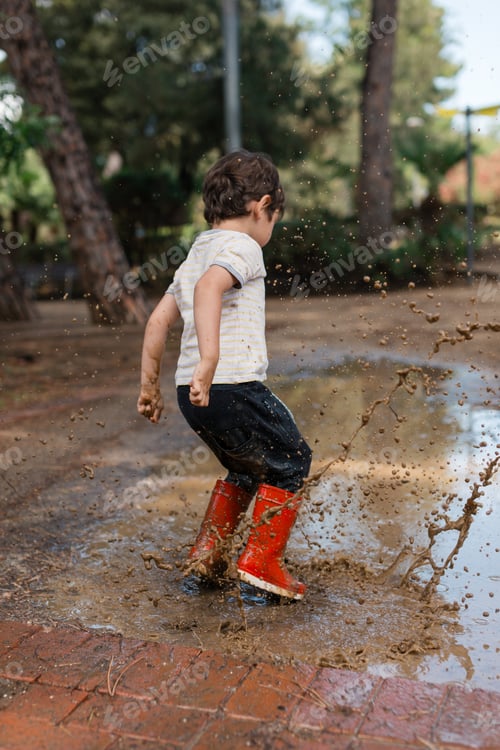 Preview: Toddler playing in mud puddle wearing red boots
