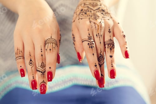 Preview: Hands decorated with henna designs and red nails in a bright indoor space
