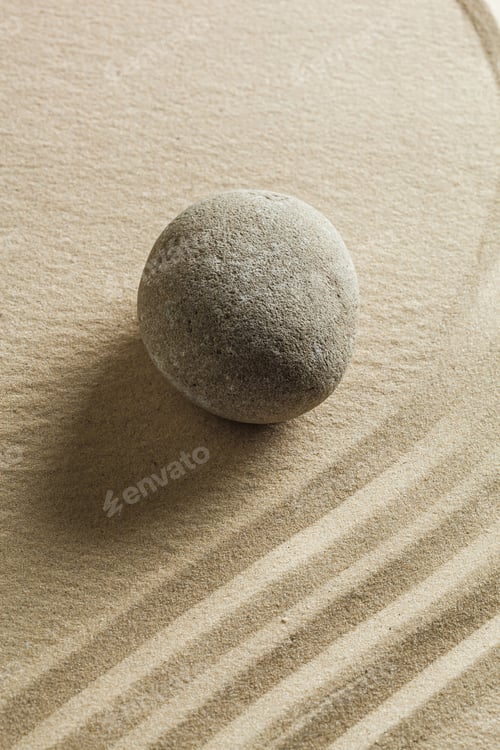 Preview: Round stone resting on smooth sand with lines formed in the surface during a quiet moment