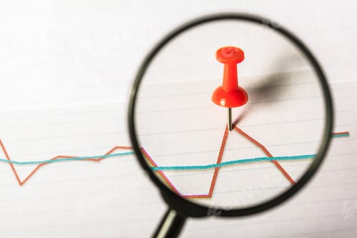 Preview: Red push pin on a graph highlighted by a magnifying glass on a white background