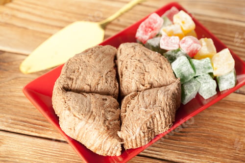Preview: Traditional sweet dish served on a red plate with jelly candies on wooden table