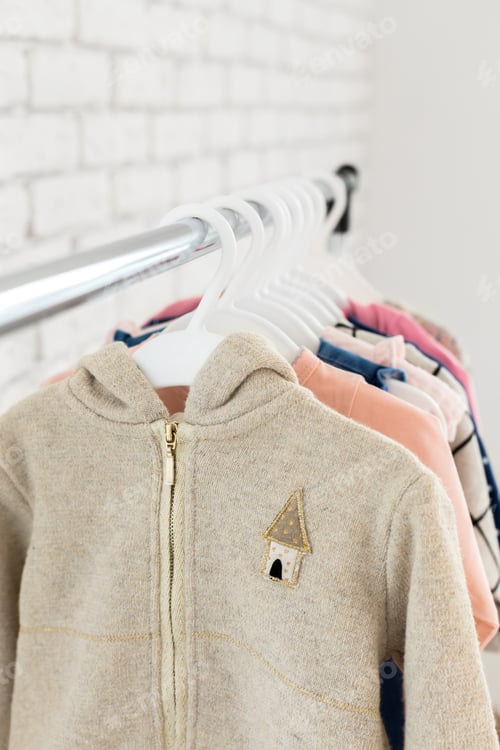 Preview: Hooded sweater hangs on rack alongside colorful shirts in a store display area