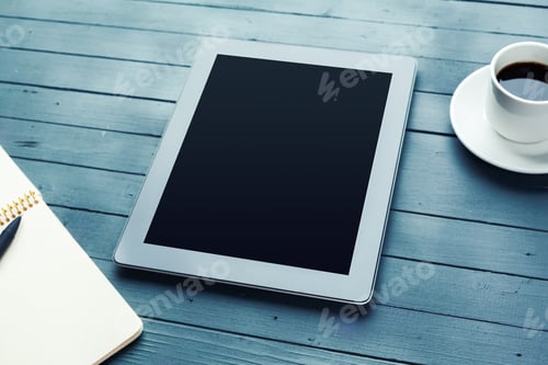Preview: People work on a tablet with a notebook and a cup of coffee on a wooden table
