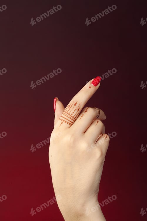 Preview: Henna design on hand with red nails pointing at dark background